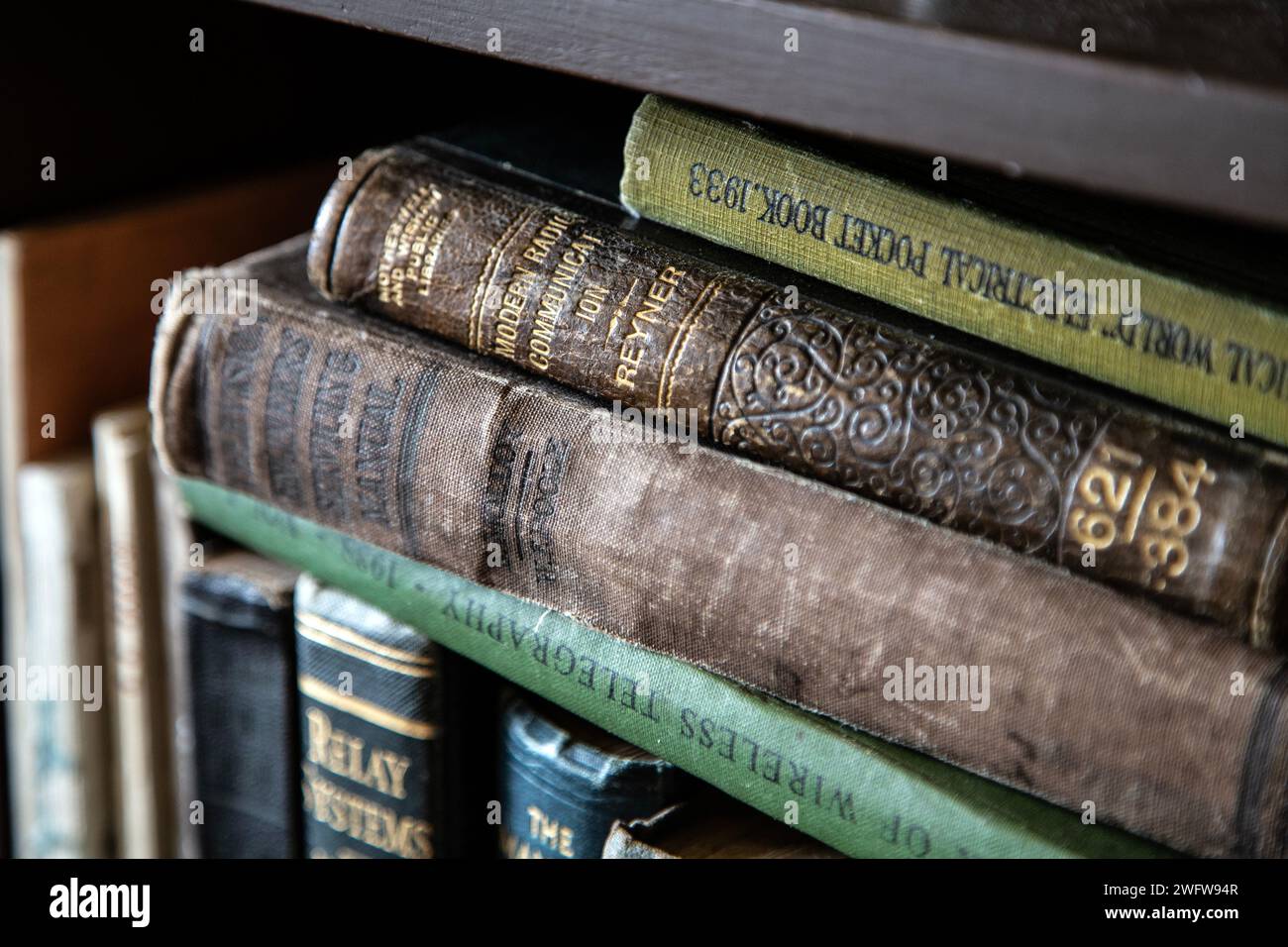 Old books on a bookshelf (Interior of Gripton's Radio Stores, a 1930s recreation of a radio shop, Black Country Living Museum, Dudley, England) Stock Photo