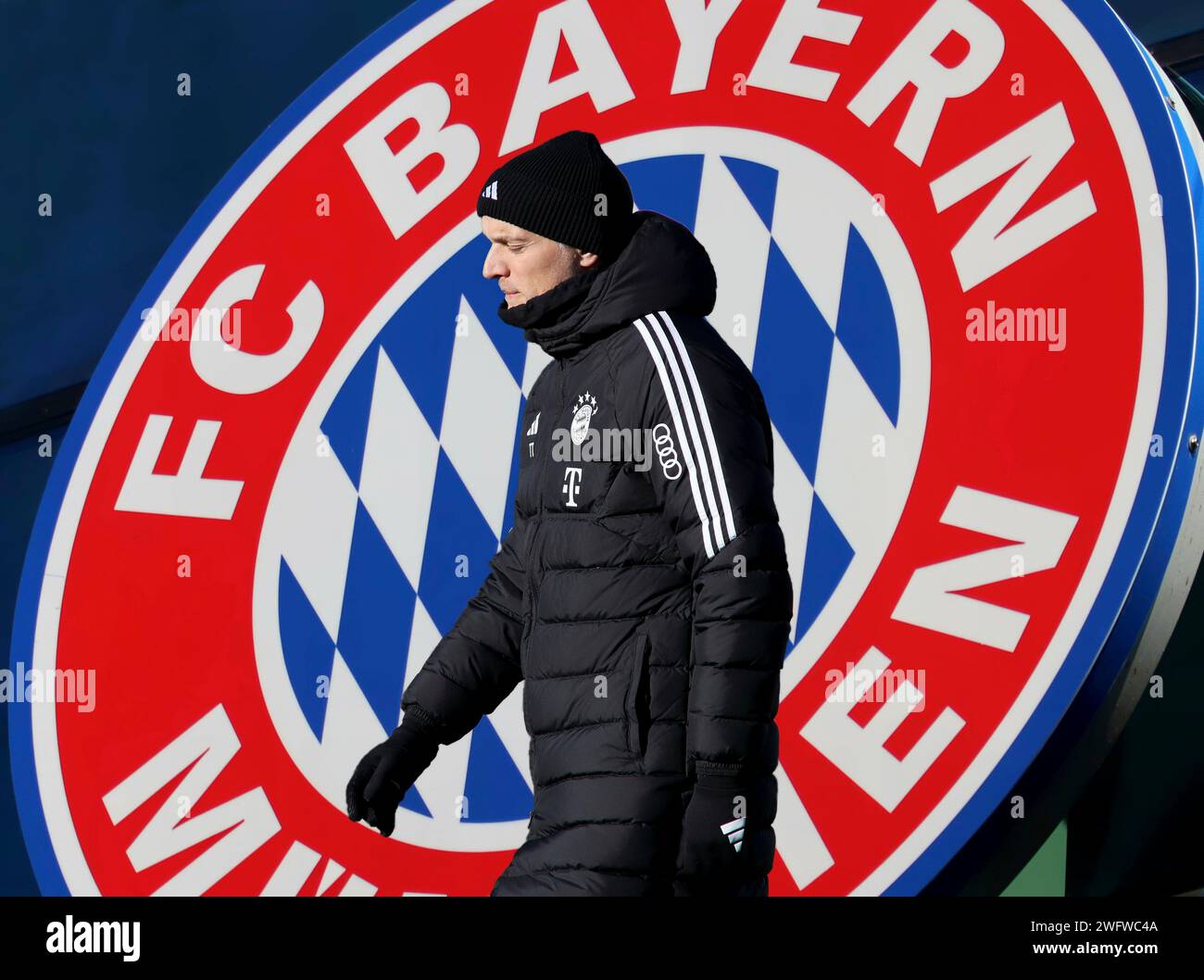 München, Deutschland 01. Februar 2024: Fussball, Herren, Saison 2023/2024, FC Bayern München ! Achtung Fotomontage ! Hier im Bild Thomas Tuchel, Trainer (FC Bayern München) gehend, bleich, krank, Grippe, nachdenklich, Kopf, Oberkörper, im Hintergrund das Logo des Vereins Stock Photo