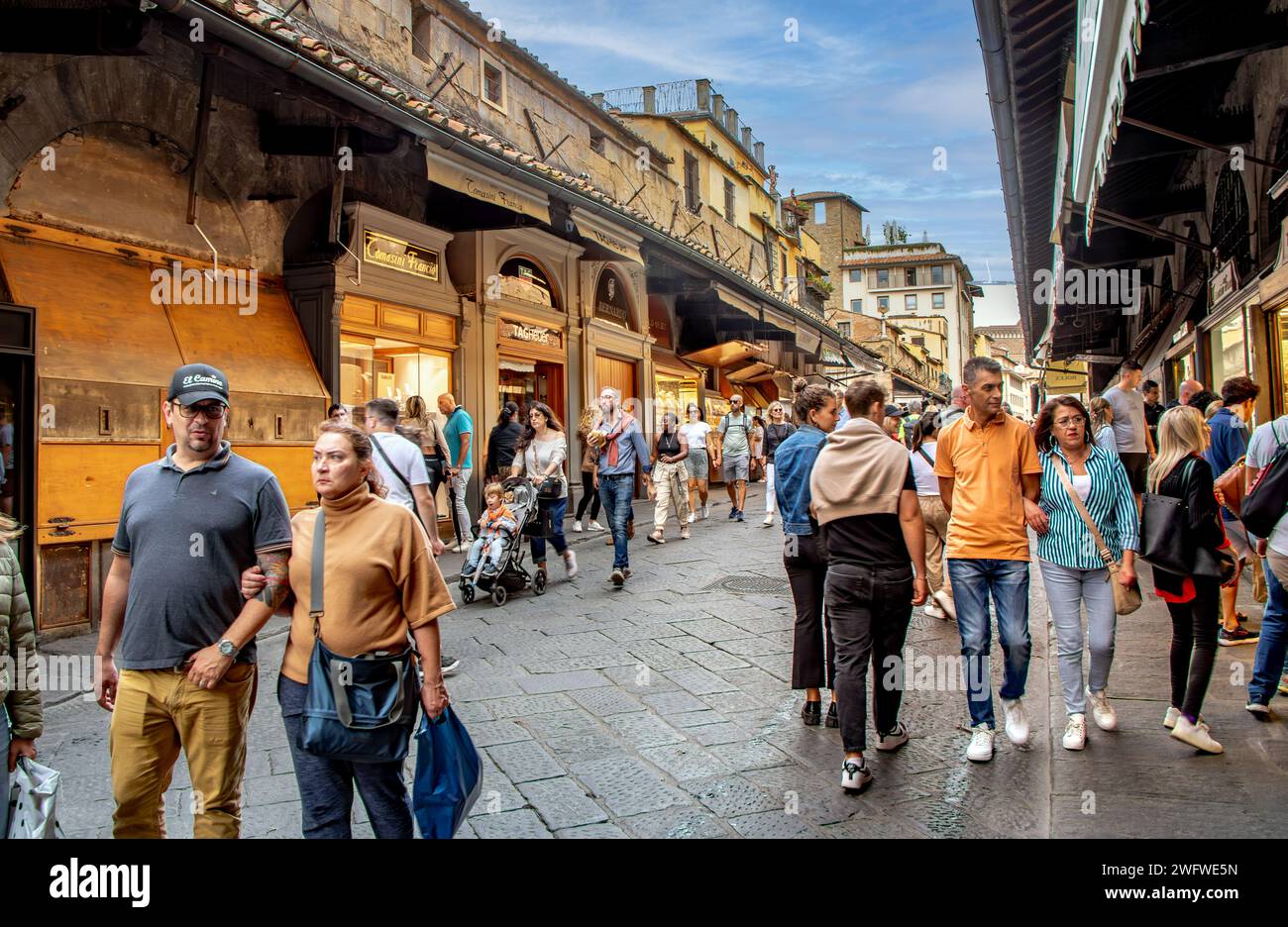 Crowds of people walking on the Ponte Vecchio bridge browsing the many
