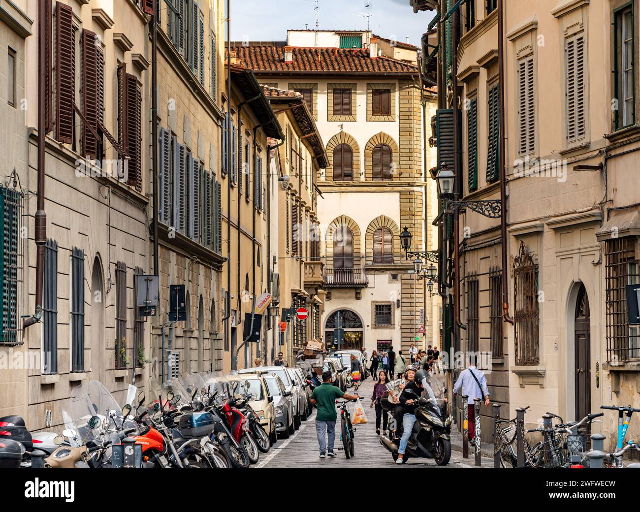 A man pushing his bicycle along a street in The Oltrano district of Florence, Italy Stock Photo