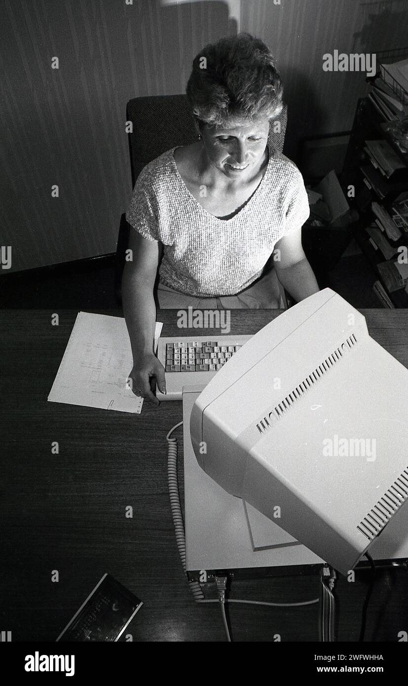 1987, historical, a view from above, at a small manufacturing business, a female office worker working at a desk with keyboard and monitor, England, UK. Stock Photo