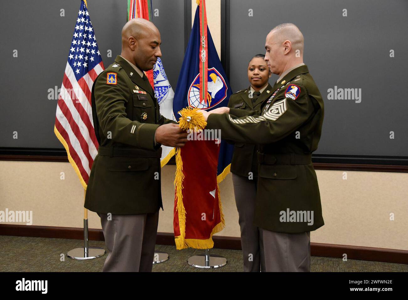 Newly promoted Lt. Gen. Sean A. Gainey, left, unfurls his three-star flag with assistance from Command Sgt. Maj. John Foley, command sergeant major, U.S. Army Space and Missile Defense Command, and Staff Sgt. Armanni Patterson, enlisted aide, during a promotion ceremony at SMDC’s Redstone Arsenal, Alabama, headquarters on Jan. 9, 2024. Stock Photo