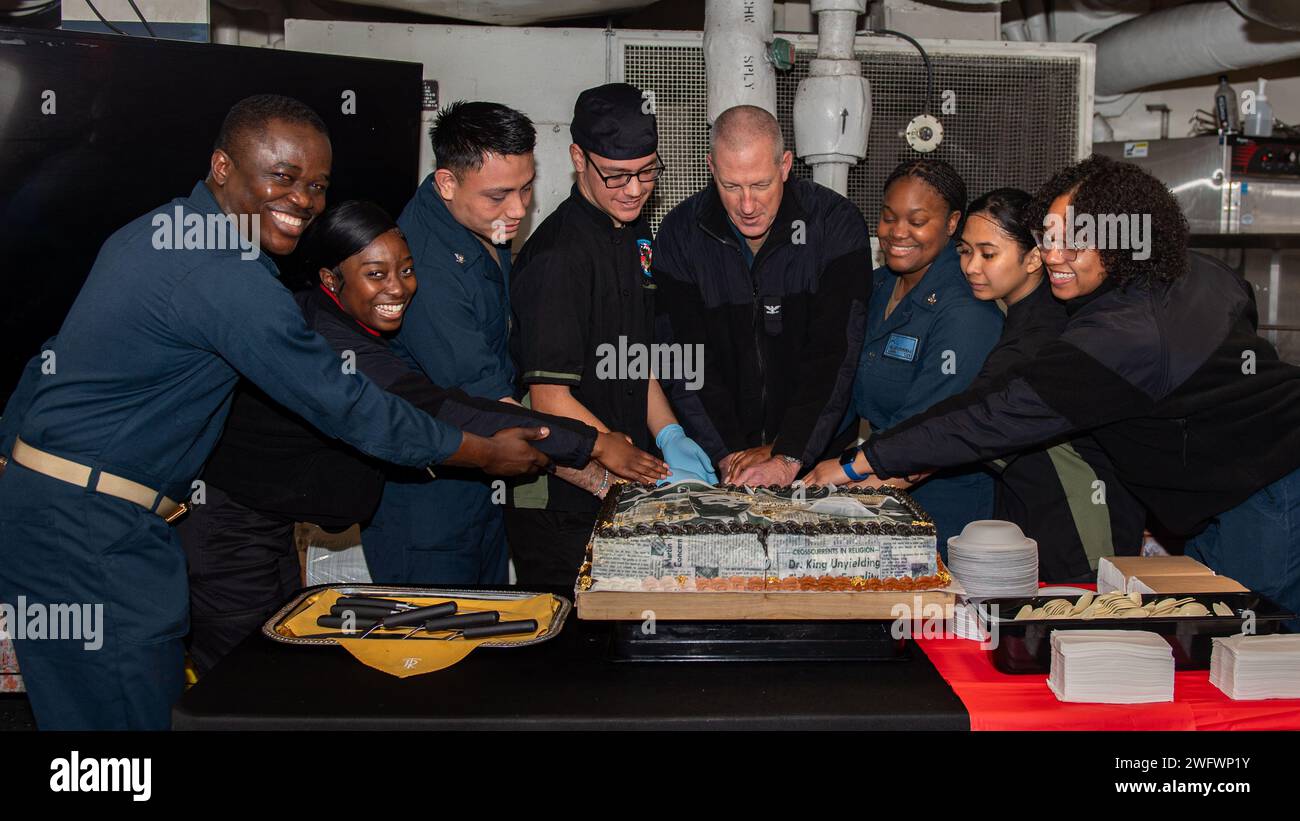 PACIFIC OCEAN (Jan. 15, 2024) U.S. Navy Capt. Brian Schrum, commanding officer of the Nimitz-class aircraft carrier USS Theodore Roosevelt (CVN 71), center, and Theodore Roosevelt Sailors cut a ceremonial cake during a Martin Luther King Jr. Day celebration, Jan. 15, 2024. Theodore Roosevelt, flagship of Carrier Strike Group Nine, is underway conducting routine operations in the U.S. 3rd Fleet area of operations. An integral part of U.S. Pacific Fleet, U.S. 3rd Fleet operates naval forces in the Indo-Pacific and provides the realistic, relevant training necessary to execute the U.S. Navy’s rol Stock Photo