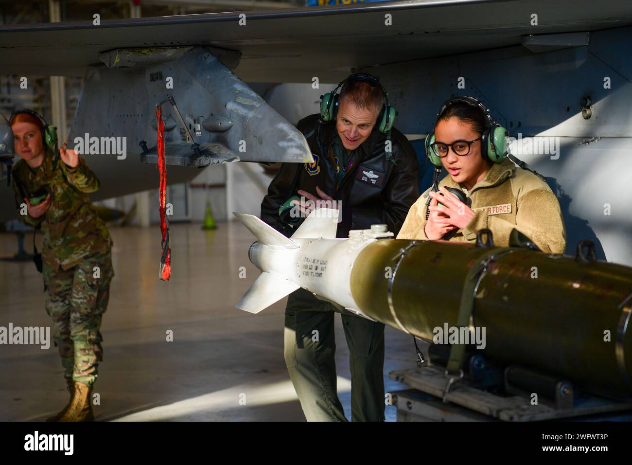 U.S. Air Force Maj. Gen. Derek France, Third Air Force commander, receives instruction from Staff Sgt. Nicole Almario, a maintainer assigned to the 31st Maintenance Squadron, right, on the process of loading munitions, at Aviano Air Base, Italy, Jan. 23, 2024. Responsible for 10 wings with more than 32,000 Airmen across two continents, the Third Air Force plans, executes and assesses a full spectrum of airpower operations across Europe and Africa. Stock Photo