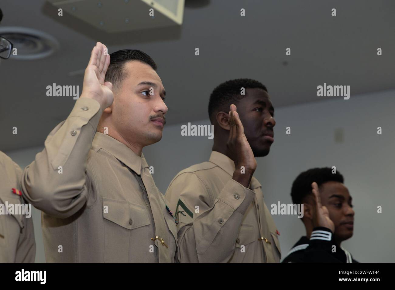 From left to right, U.S. Marine Corps Cpl. Jeferson HernandezEscobar, a motor vehicle operator with Combat Logistics Company 36, Combat Logistics Regiment 37, Lance Cpl. Cyrus Fayiah, an electrician with Marine Wing Support Squadron 171, Marine Aircraft Group 12, and U.S. Navy Aviation Mechanic Seaman Alwayne Cowie, assigned to Strike Fighter Squadron (VFA) 27, Carrier Air Wing (CVW) 5, swear in during a naturalization ceremony at Marine Corps Air Station Iwakuni, Japan, Jan. 30, 2024. The naturalization ceremony was held to acknowledge MCAS Iwakuni service members’ becoming citizens of the Un Stock Photo