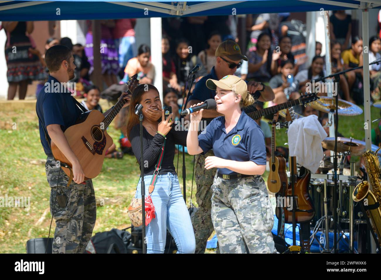 Royal Australian Navy Able Seaman (Musician) Maggie James sings with the Pacific Partnership Band, comprised of members from the U.S. Pacific Fleet Band and Royal Australian Navy Band, at Chuuk High School during a host nation outreach event in Chuuk, Federated States of Micronesia, as part of Pacific Partnership 2024-1 Jan. 15, 2024. Pacific Partnership, now in its 19th iteration, is the largest multinational humanitarian assistance and disaster relief preparedness mission conducted in the Indo-Pacific and works to enhance regional interoperability and disaster response capabilities, increase Stock Photo