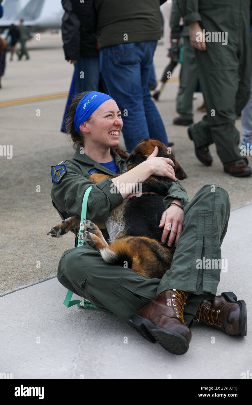 240115-N-YM590-1113 VIRGINIA BEACH, Va. (Jan. 15, 2024)- A pilot, assigned to the “Fighting Blacklions” of Strike Fighter Squadron (VFA) 213, reunites with her dog after returning to Naval Air Station Oceana in Virginia, Jan. 15, following a more than eight-month deployment with the Gerald R. Ford Carrier Strike Group. While deployed, the squadron accomplished 1,943 sorties covering 3,137 flight hours with a 97% sortie completion rate. Stock Photo