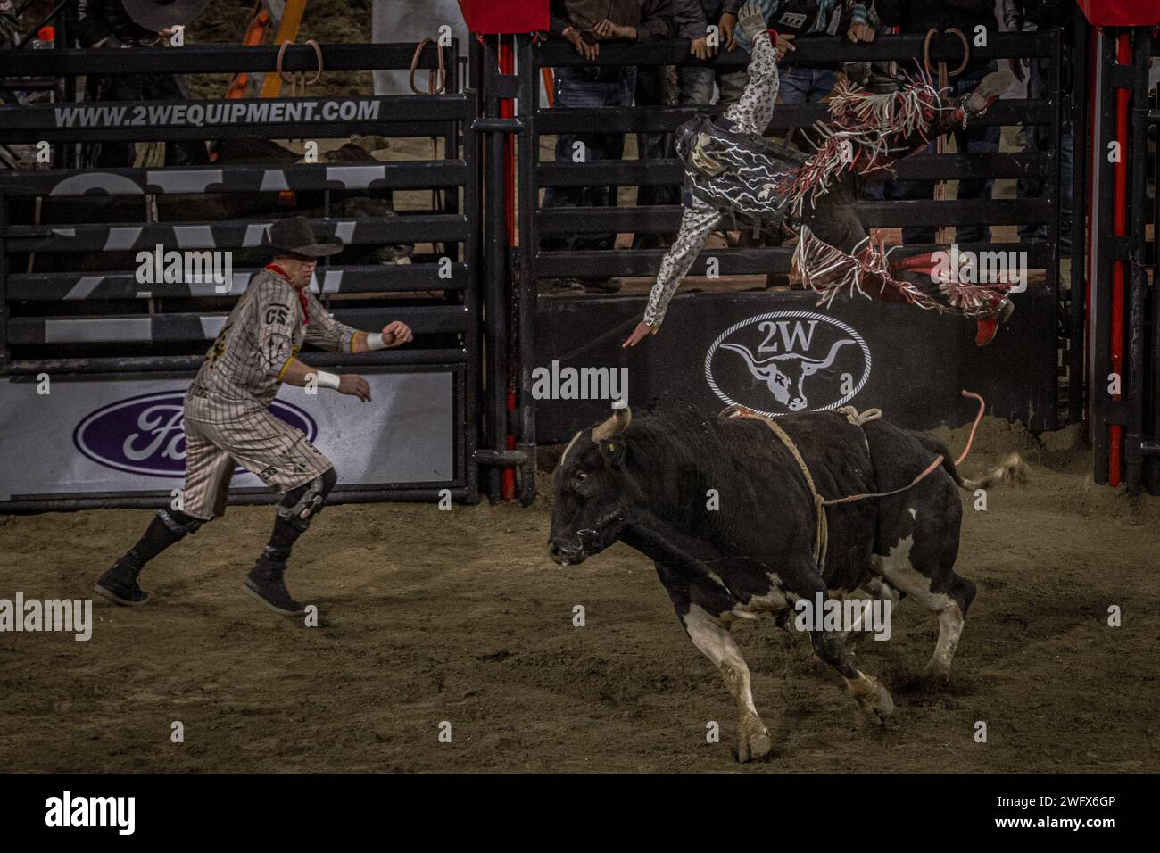 An individual prepares to distract the bull as its rider falls off as a part of the San Diego