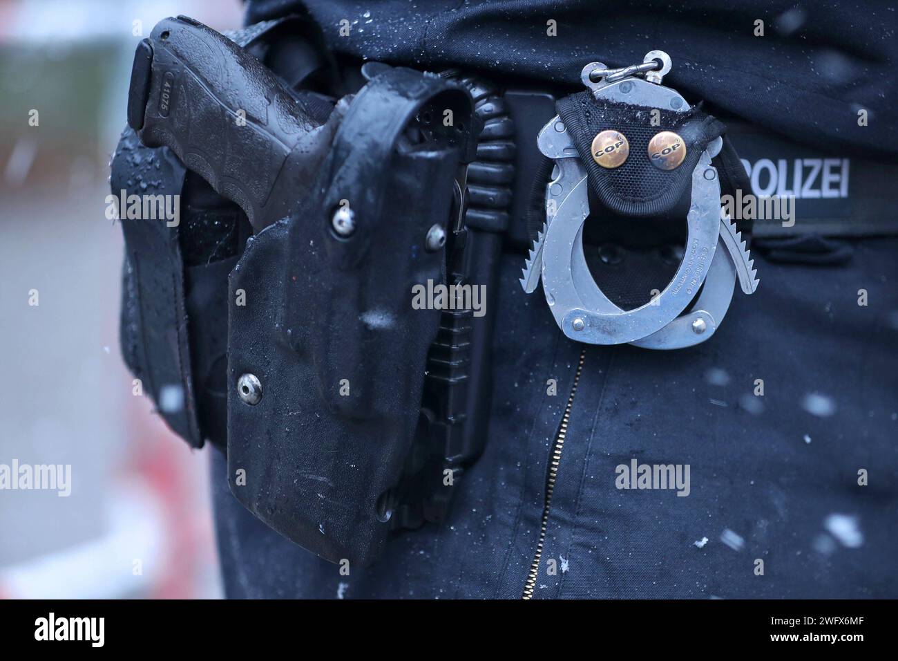 15.01.2024, Berlin, Handschellen und Handfeuerwaffe im Pistolen Holster am Gürtel eines Polizisten in Nahaufnahme Berlin Deutschland *** 15 01 2024, Berlin, Handcuffs and handgun in pistol holster on the belt of a policeman in close-up Berlin Germany Stock Photo