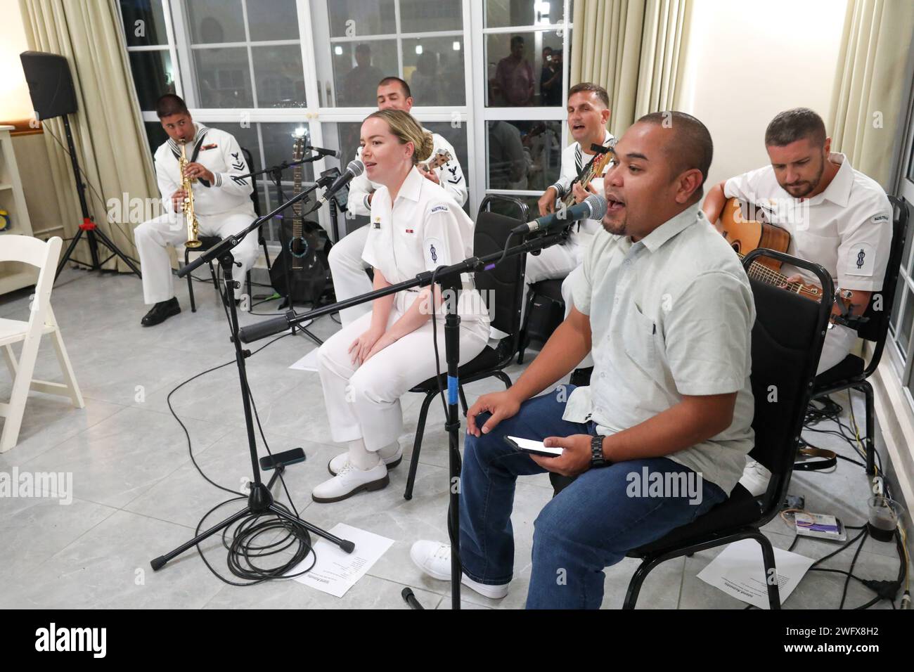 The Pacific Partnership Band, consisting of U.S. Navy and Australian sailors, play with a local vocalist during the mission stop closing ceremonies in Koror, Palau, as part of Pacific Partnership 2024-1 Jan. 4, 2024. Now in its 19th iteration, Pacific Partnership is the largest annual multinational humanitarian assistance and disaster relief preparedness mission conducted in the Indo-Pacific. Stock Photo
