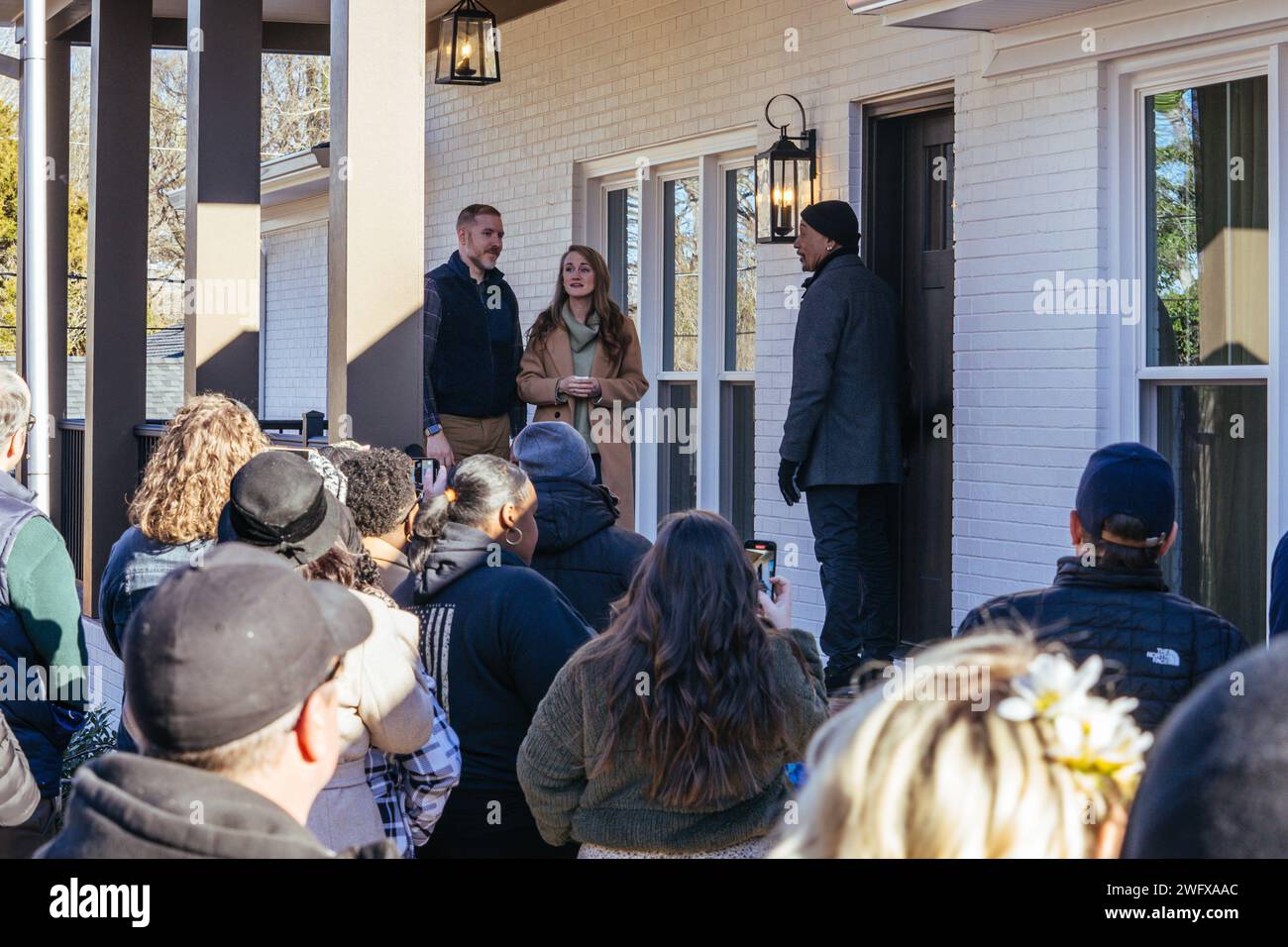 U.S. Army Staff Sgt. Jason Bowman and his wife, Sydney Bowman, listen to a cheering crowd as Montel Williams, the host of Military Makeover, officially reveals the restoration of Bowman’s home in Statesville, North Carolina, Jan. 21, 2024. Military Makeover, a television series dedicated to honoring deserving military families, and Purple Heart Homes, a local military non-profit that improves Service-Connected Disabled Veterans and their families housing, renovated the home of Bowman, a Raleigh native and soldier assigned to the NCNG’s Delta Company, 236th Brigade Engineer Battalion, 30th Armo Stock Photo
