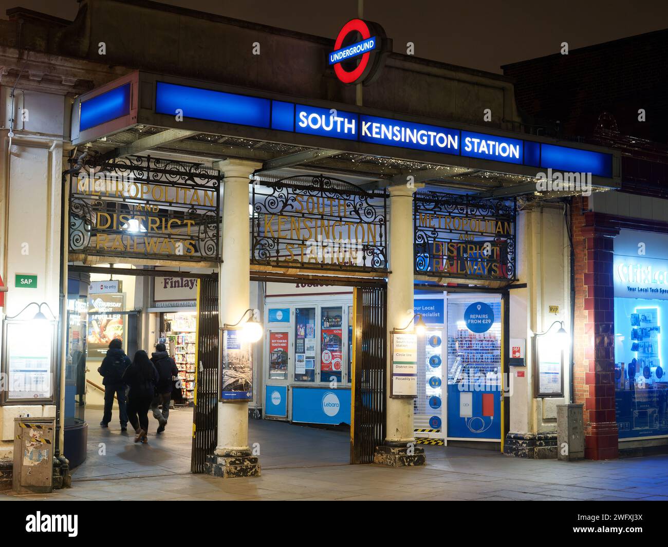 View of the colourful entrance to South Kensington tube station on the London Underground at night Stock Photo
