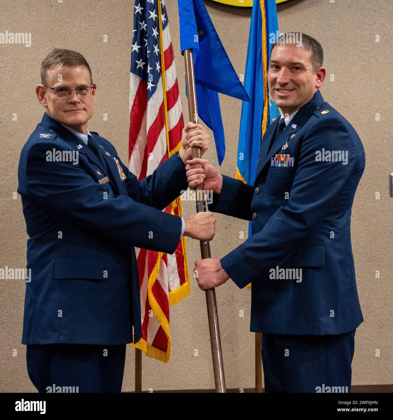 U.S. Air Force Lt. Col. Lonny Reese (left), commander of the 114th Mission Support Group, passes the 114th Civil Engineer Squadron (CES) guidon to Maj. Benjamin D. Shafer, incoming 114th CES commander during a change of command ceremony at Joe Foss Field, South Dakota, Jan. 7, 2024. The primary aim of the ceremony is to allow the team members to witness the formality of command change from one officer to another. Stock Photo