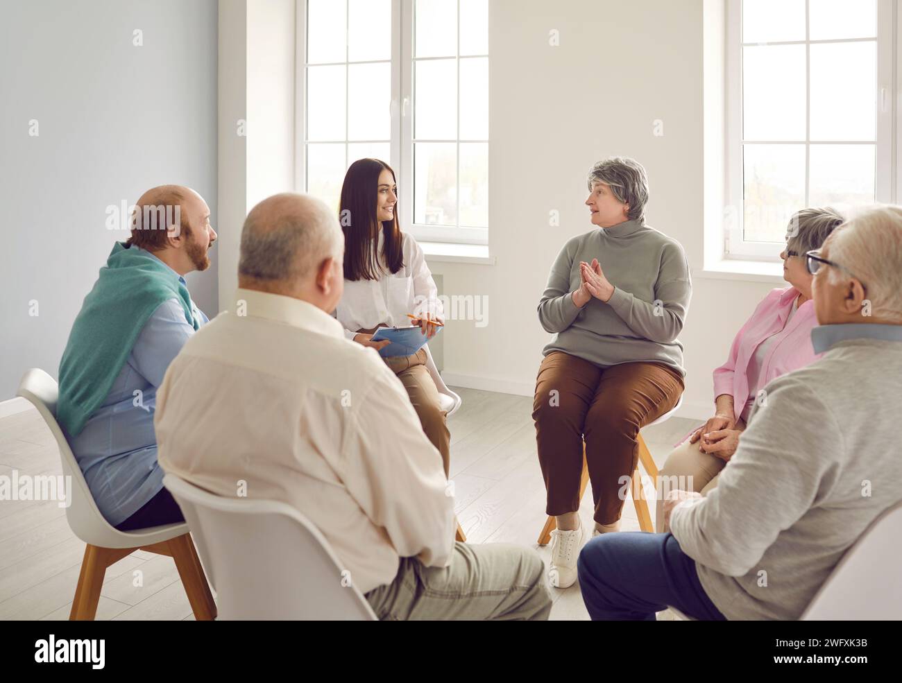 Several senior people sharing and discussing their problems at group therapy meeting Stock Photo