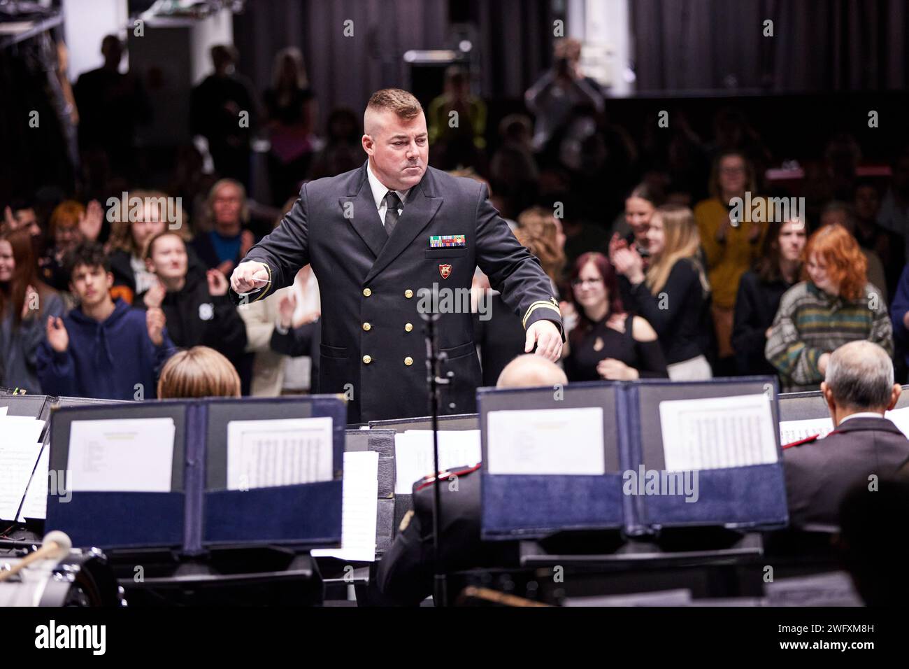 U.S. Navy Lt. j.g. Matt Stuver, assistant director, U.S. Naval Forces Europe and Africa band, conducts during a concert at Vaskivuori High School, in Vantaa, Finland, Jan. 30, 2024. The event included a workshop and culminated in a performance aimed at fostering interaction and mentorship between the service members and the school's students. Stock Photo