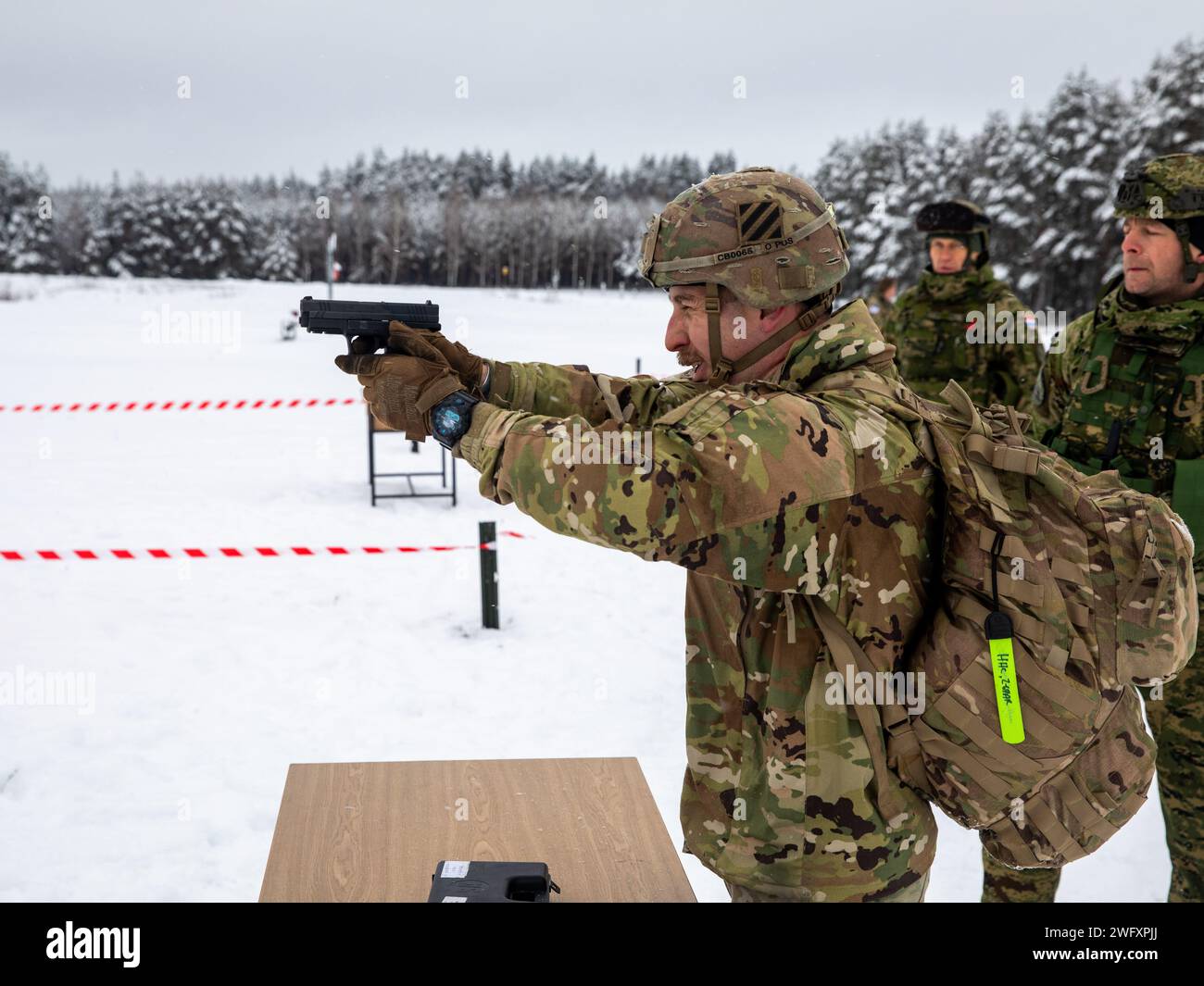 U.S. Army Sgt. Chris Bates, an intelligence analyst with Headquarters and Headquarters “Hazard” Company, 2nd Battalion, 69th Armored Regiment “Panther Battalion,” 2nd Armored Brigade Combat Team, 3rd Infantry Division, fires an HS-9 pistol during the Croatian “Winter Challenge” at Bemowo Piskie Training Area, Poland, Jan. 5, 2024. The Croatian “Winter Challenge” is a 15-kilometer competition consisting of seven events: land navigation, small arms firing, wall climbing, obstacle course while wearing a gas mask, rope crossing, low-crawl and obstacle climbing, and a hand grenade toss. U.S., Polis Stock Photo