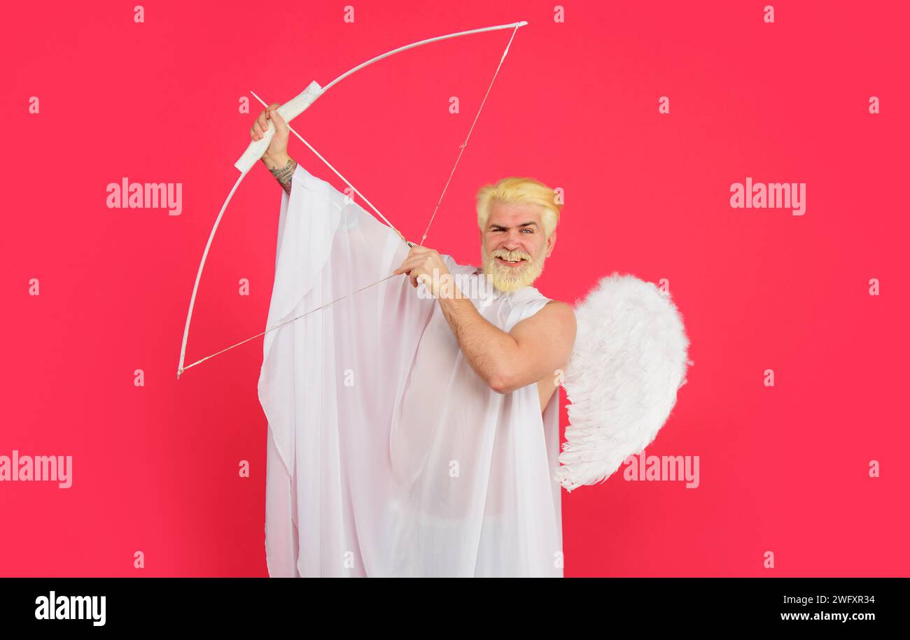 Valentines day. Love and romance. Smiling male angel aiming with bow and arrow. Valentine cupid in angel wings shooting arrow of love from bow Stock Photo