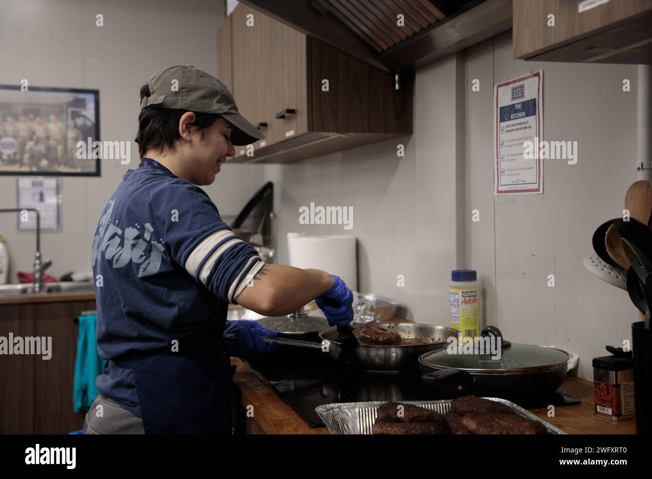 U.S. Army Sgt. Victoria Mirabile, a network communication systems specialist assigned to 414th Signal Company in 3rd Division Sustainment Brigade, 3rd Infantry Division, cooks hamburgers during the Martin Luther King Jr. barbecue in Powdiz, Poland, on Jan. 15, 2024.  Martin Luther King, Jr. Day, observed on the third Monday of January each year, marks the birthday of the civil rights leader and activist. In 1994, Congress designated Martin Luther King, Jr. Day as a national day of service. The theme of the day, “A Day On, Not a Day Off,” encourages individuals to dedicate the day to community Stock Photo