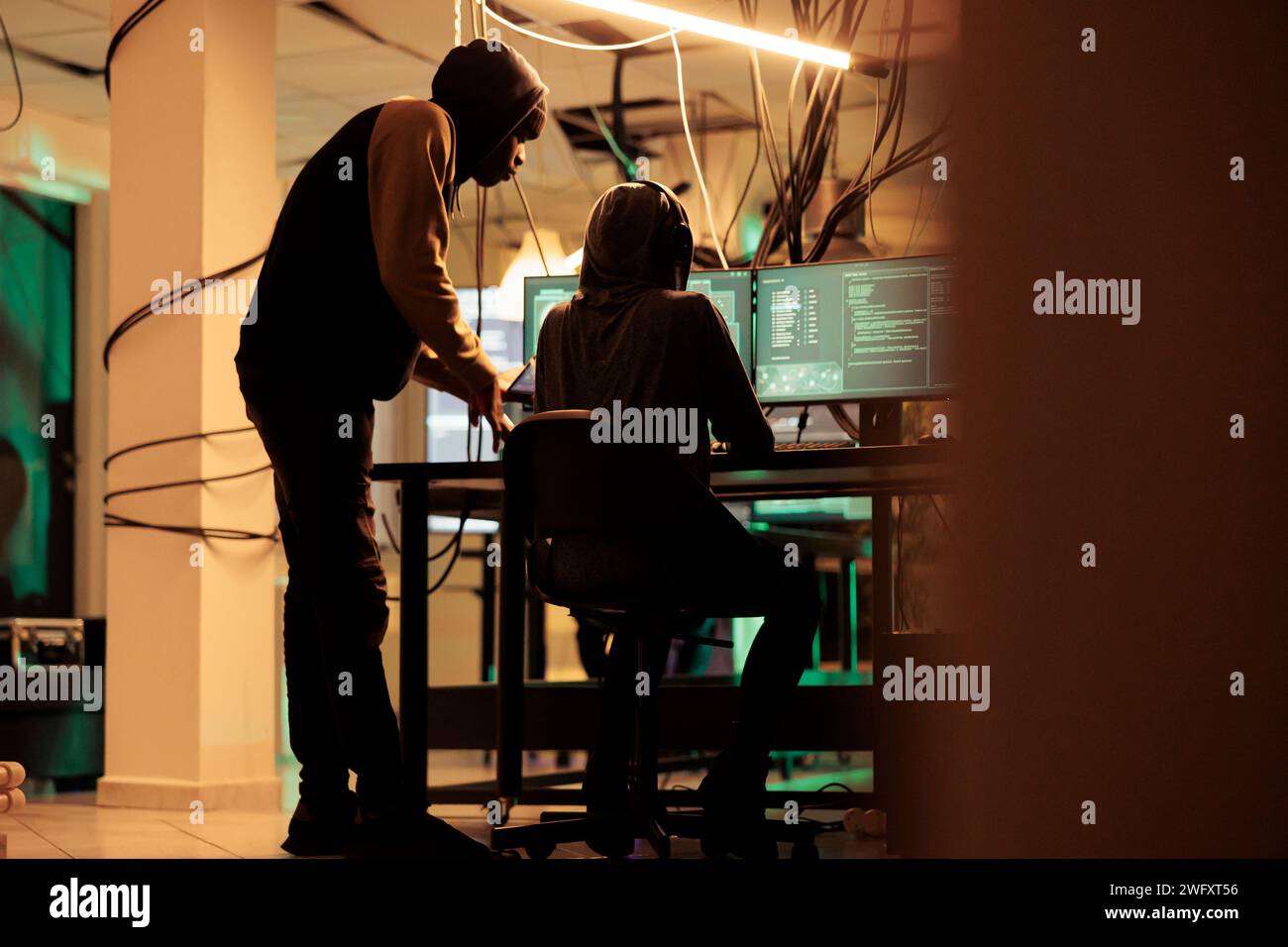 Online criminals analyzing script codes to hack government system, attacking sensitive sever and causing security breach. People hacking network and stealing information at night. Stock Photo