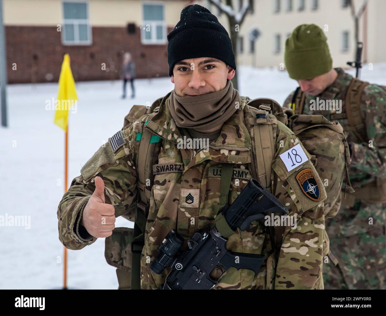 U.S. Army Staff Sgt. Eli J. Swartz, a fire direction controller with Headquarters and Headquarters “Hazard” Company, 2nd Battalion, 69th Armored Regiment “Panther Battalion,” 2nd Armored Brigade Combat Team, 3rd Infantry Division, gives a thumbs-up before beginning the Croatian “Winter Challenge” at Bemowo Piskie Training Area, Poland, Jan. 5, 2024. The Croatian “Winter Challenge” is a 15-kilometer competition consisting of seven events: land navigation, small arms firing, wall climbing, obstacle course while wearing a gas mask, rope crossing, low-crawl and obstacle climbing, and a hand grenad Stock Photo