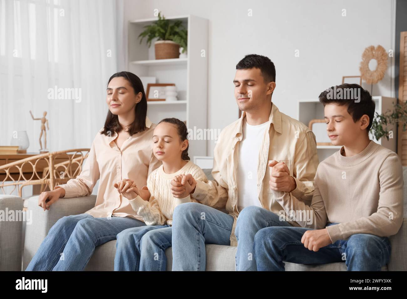 Family praying on sofa at home Stock Photo