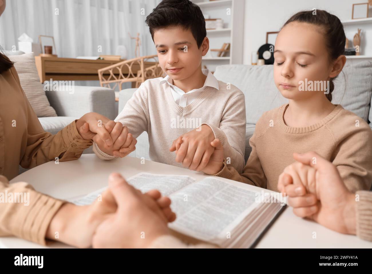 Family praying with Holy Bible on table at home Stock Photo