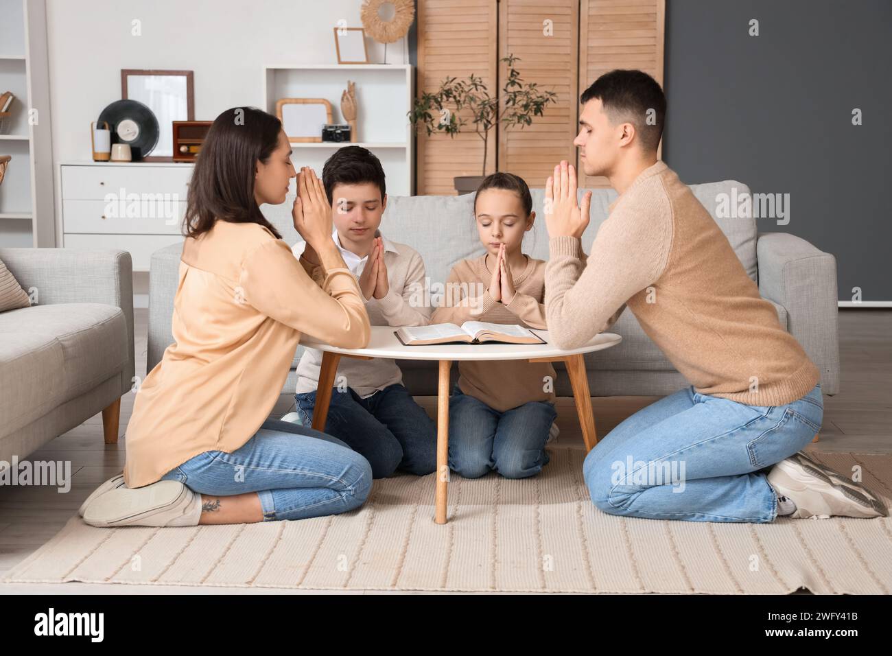 Family praying with Holy Bible on table at home Stock Photo