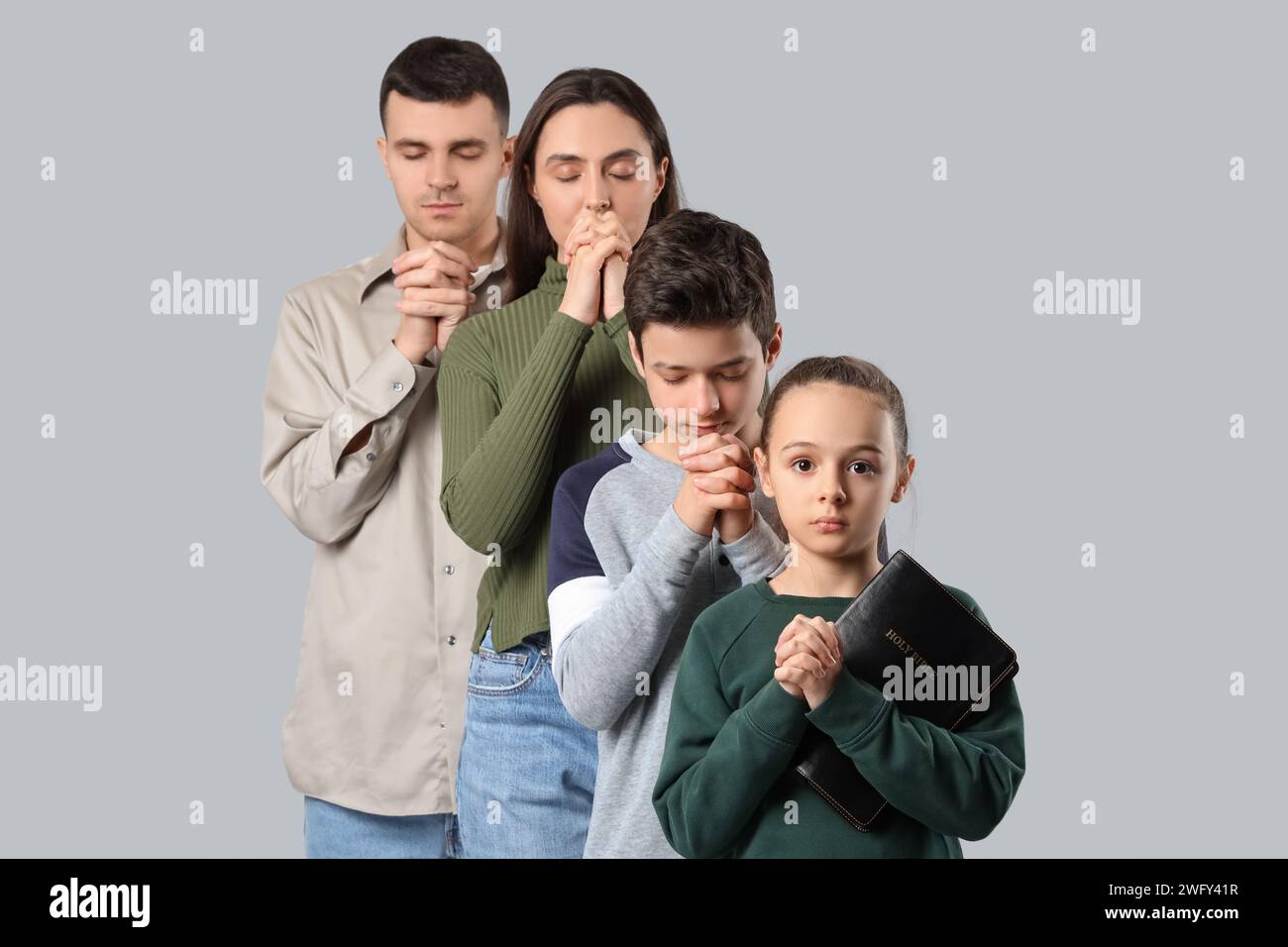 Family praying together on light background Stock Photo