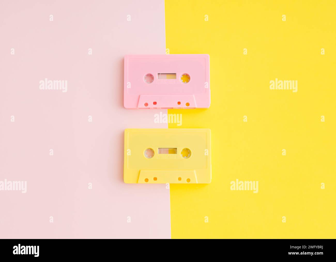 Layout of retro pink and yellow audio cassette tapes on pastel  pink and yellow background. Creative concept of retro technology. 80's aesthetic. Stock Photo