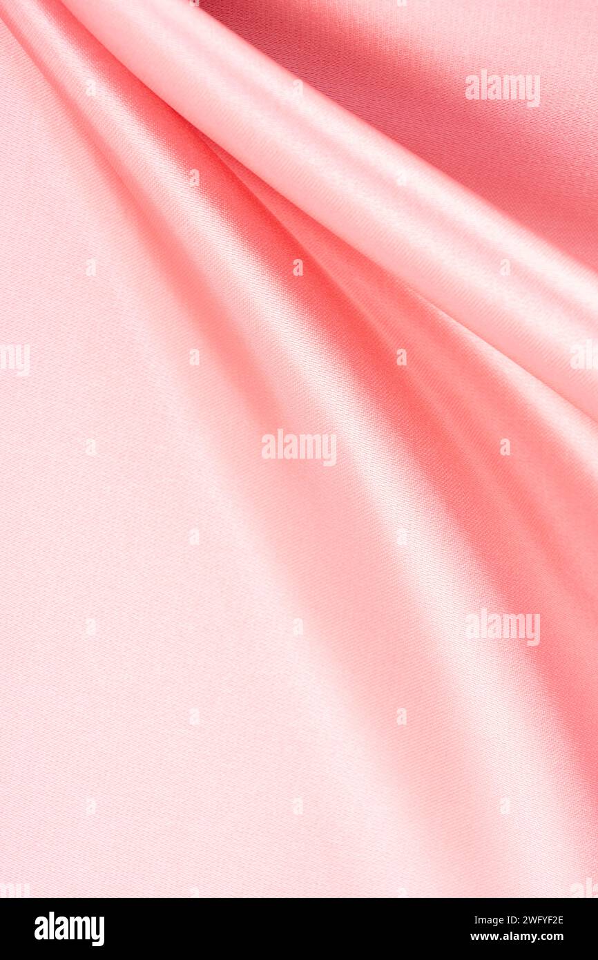 Silk satin wavy twirl fabric texture pink color. Stock Photo