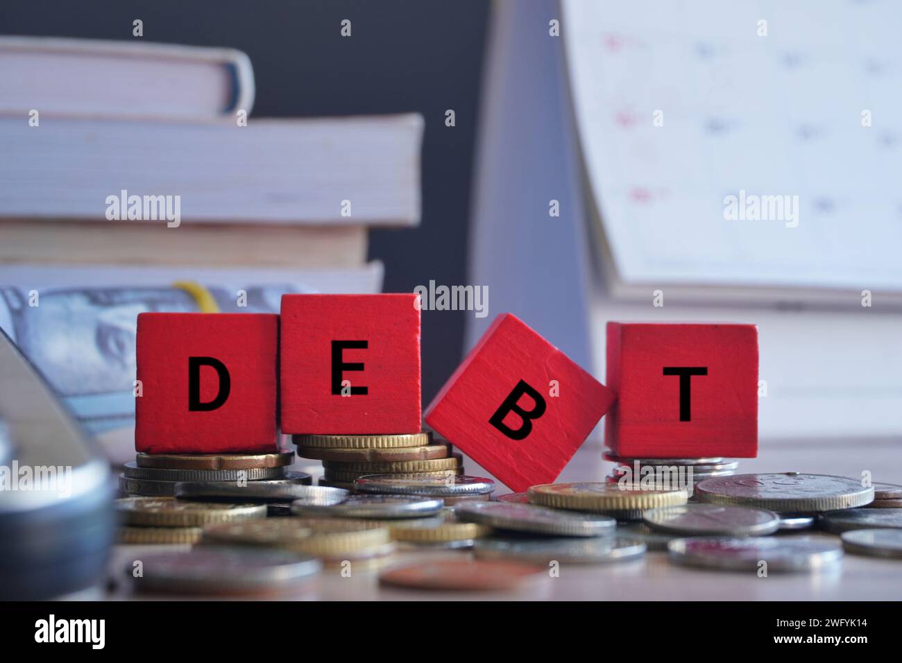 Wooden cubes with word DEBT surrounded by money and calculator. Financial concept. Stock Photo