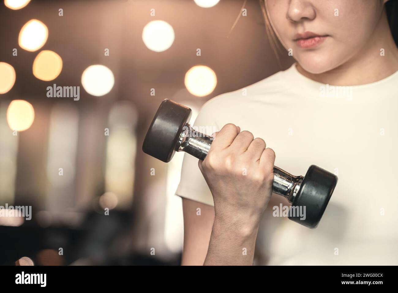 Fitness asian woman doing exercise and lifting dumbbells weights at sport gym. Stock Photo