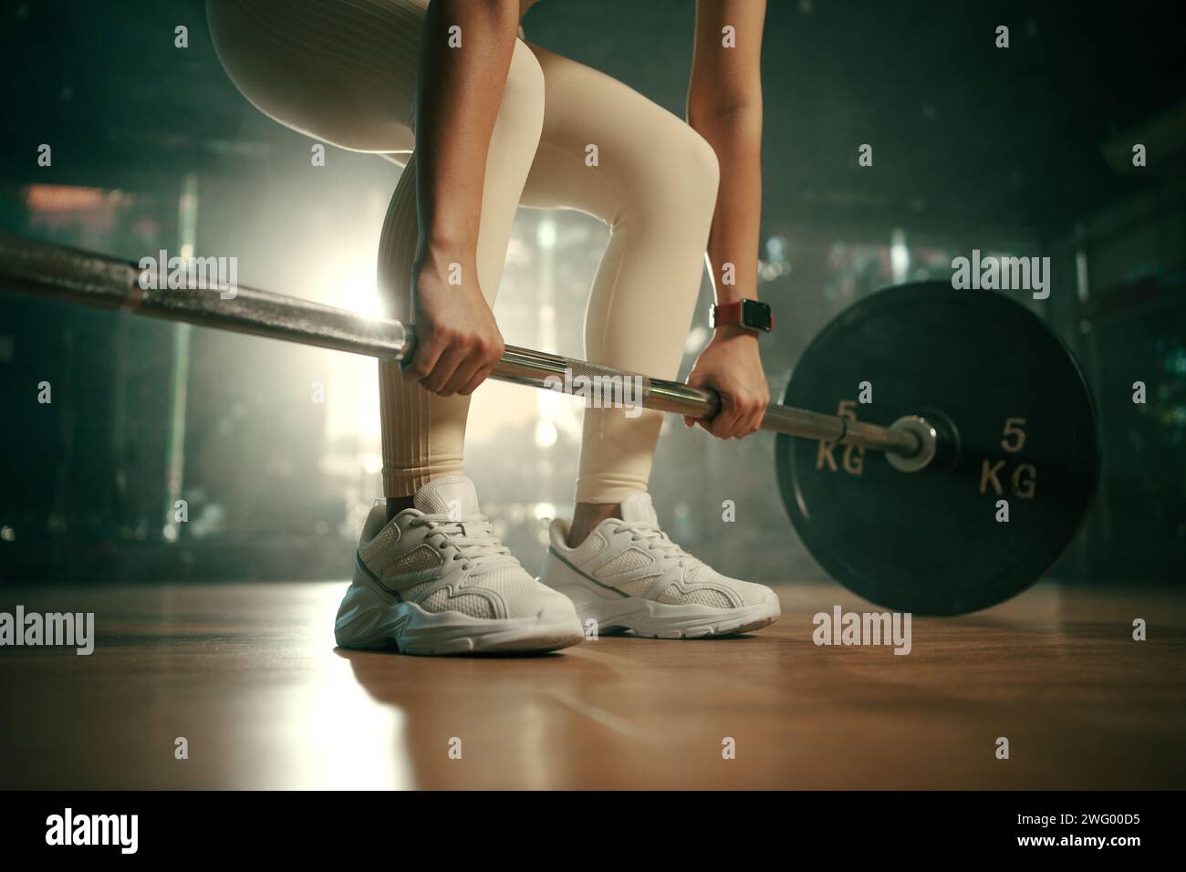 Young woman doing deadlift with heavy bar in gym, strong female athlete with muscular body lifting weights, exercising with barbell. Stock Photo