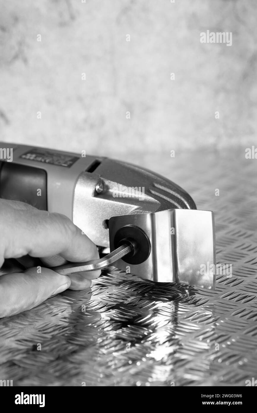 Man attaching cutting blade on an electric multi tool cutter sander. On a checker plate surface. Stock Photo