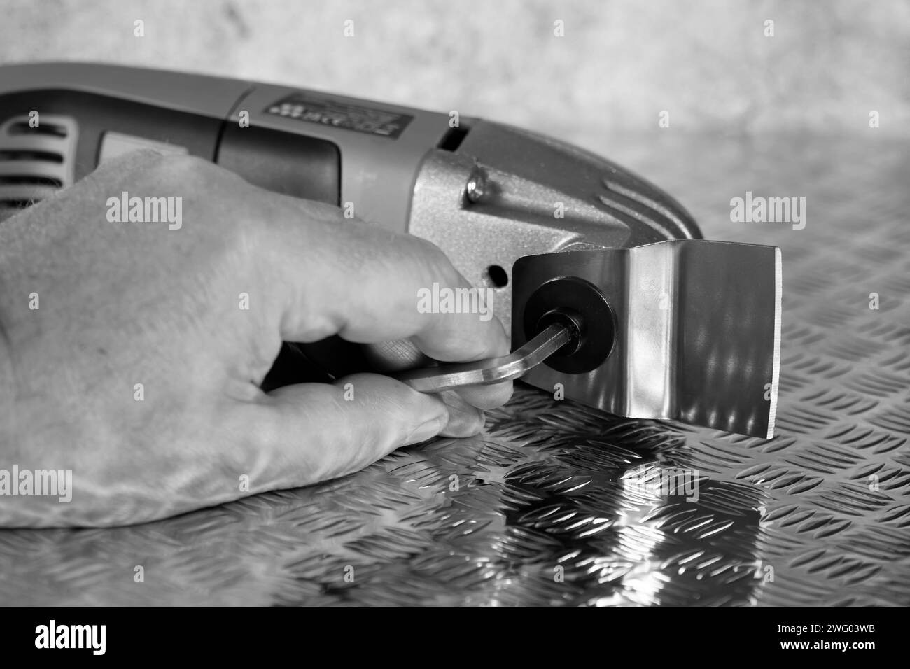 Man attaching cutting blade on an electric multi tool cutter sander. On a checker plate surface. Stock Photo