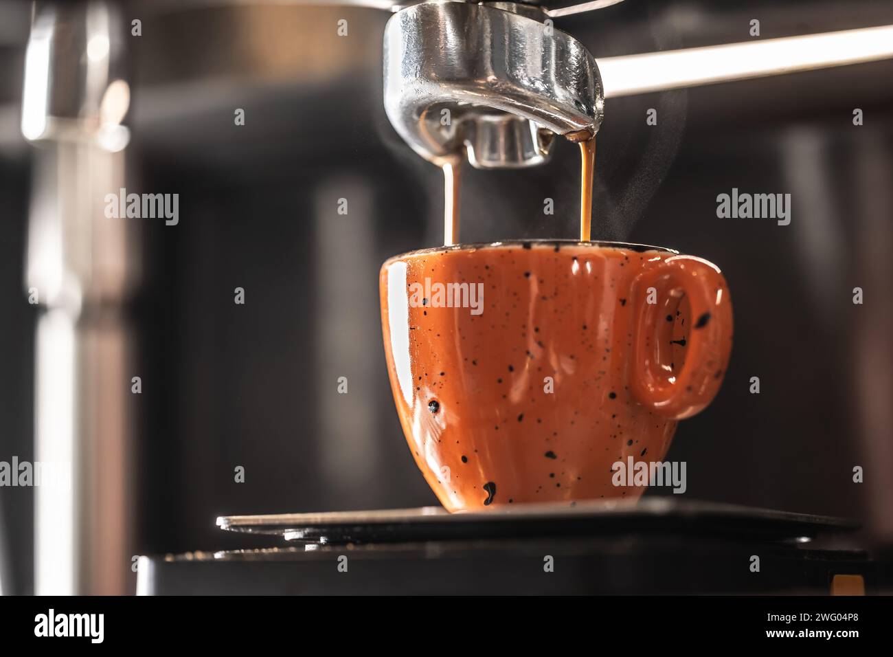 The coffee machine makes coffee into an orange cup. Stock Photo