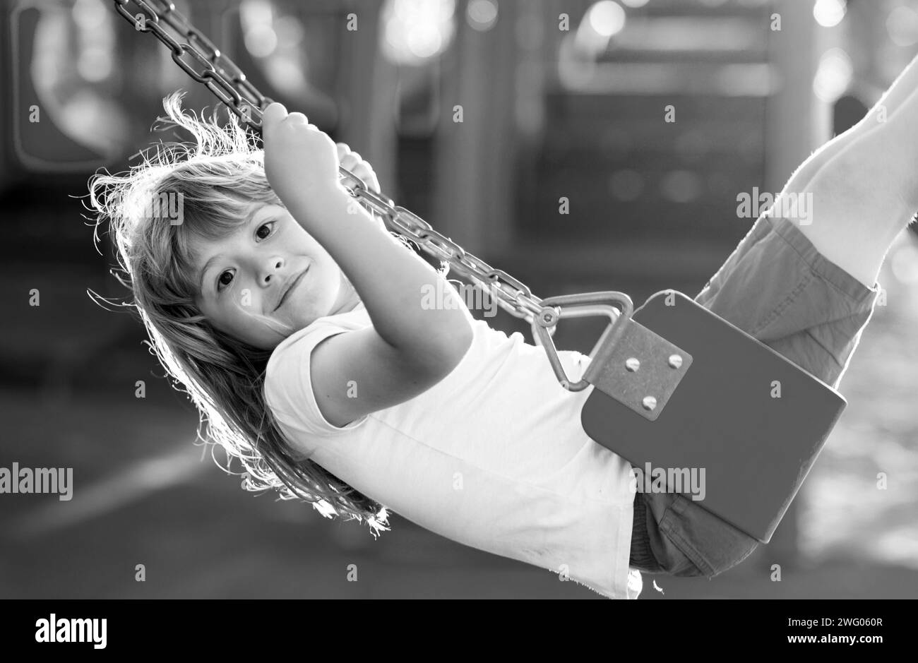 Child swinging on the playground. Cute little kid boy funny while ...