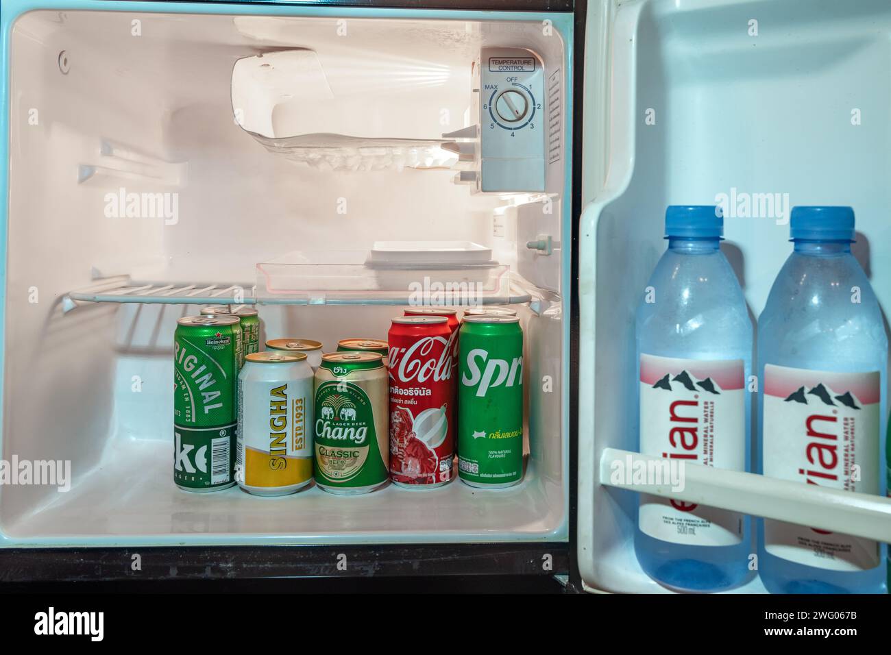 Trad, Thailand - January 24, 2024 - Cold bottles of water and soda stacking inside a small refrigerator door and the main section Stock Photo