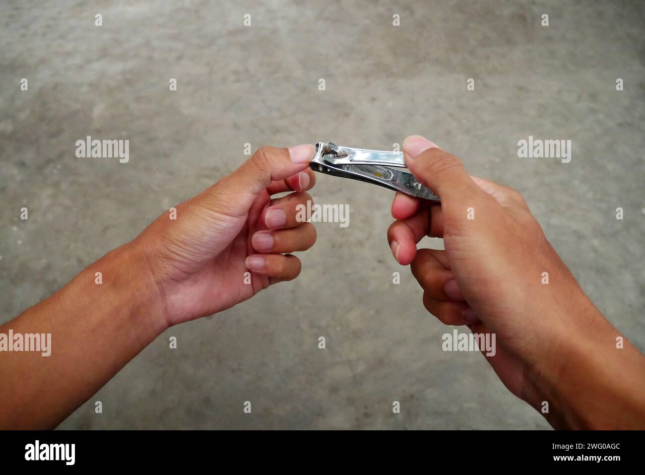 Asian man's fingernails are long and dirty. Man cutting with dirty nail scissors. Stock Photo