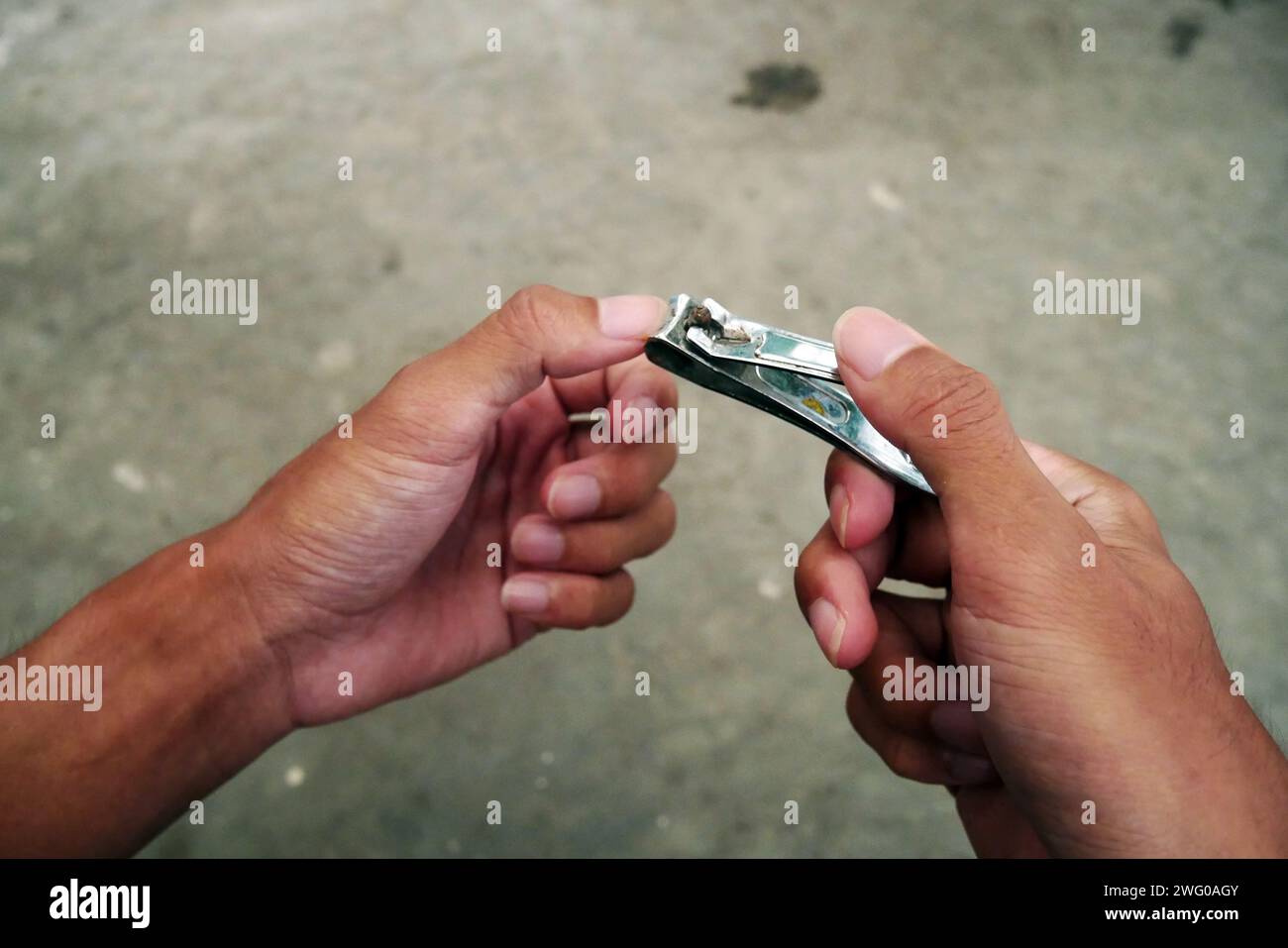 Asian man's fingernails are long and dirty. Man cutting with dirty nail scissors. Stock Photo