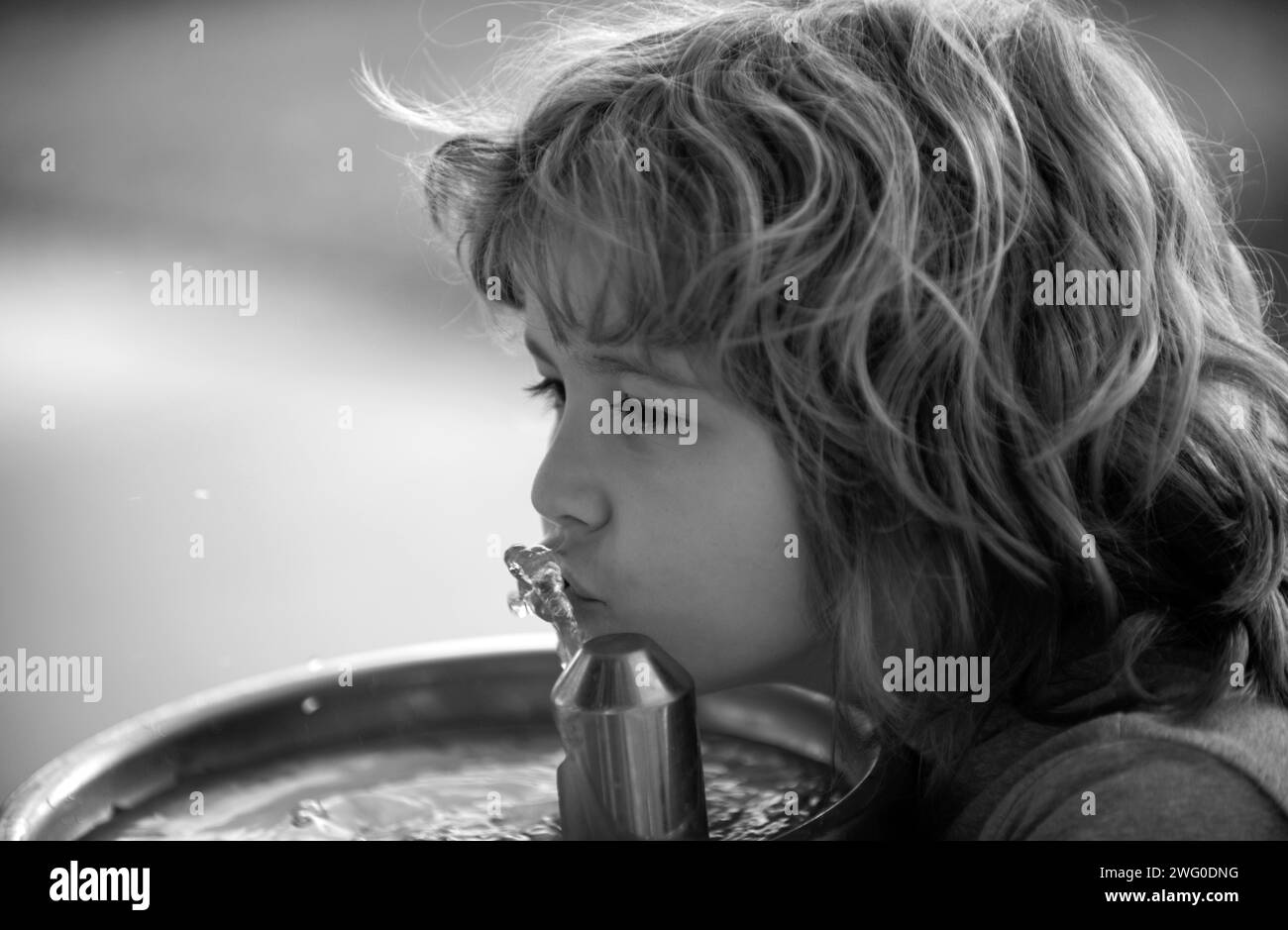 Close up portrait of kid boy drinking water from outdoor water fountain