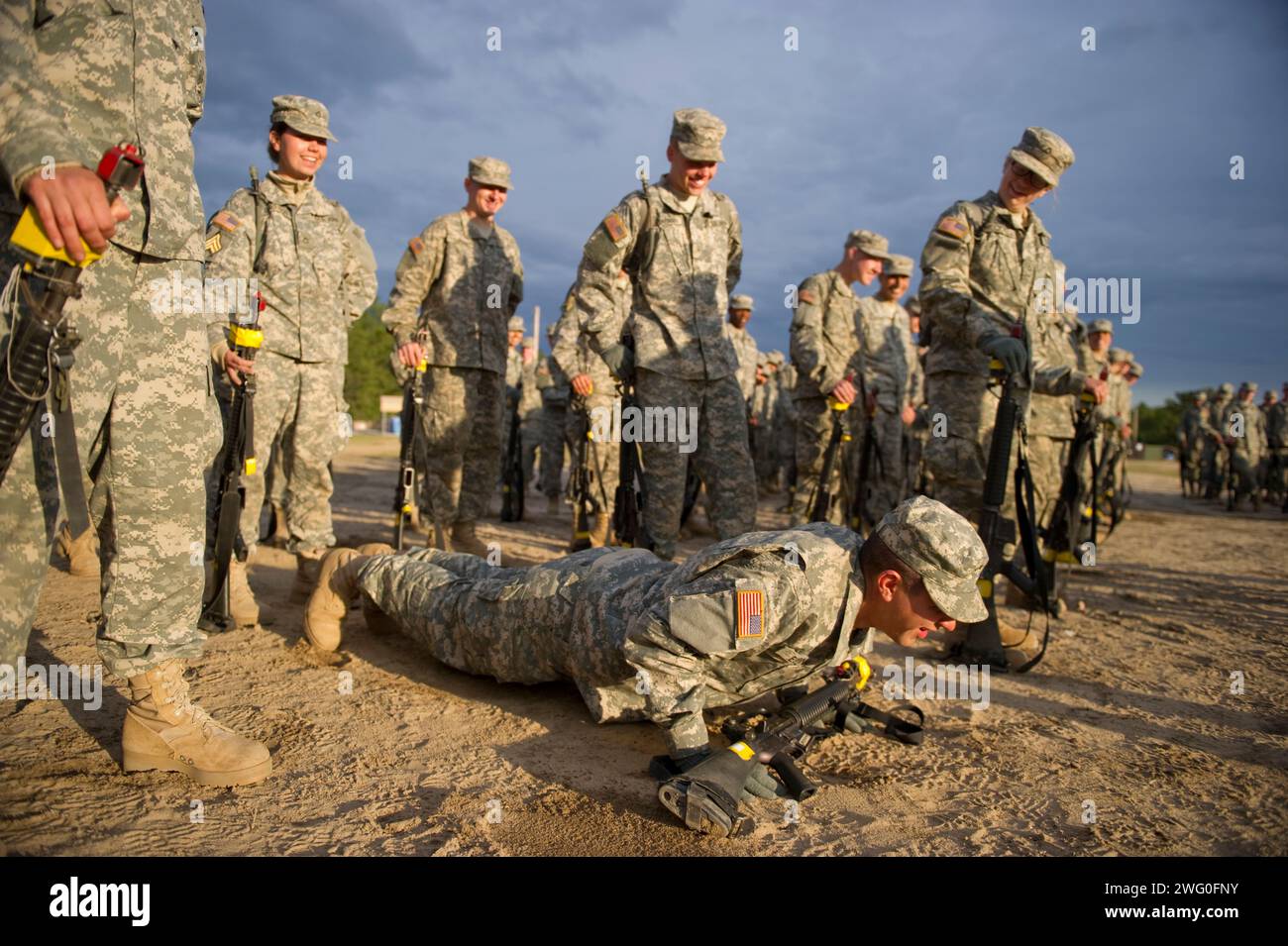 After getting yelled at by his drill sergeant, a soldier in basic training does push-ups as his rifle rests safely on his hands. Stock Photo