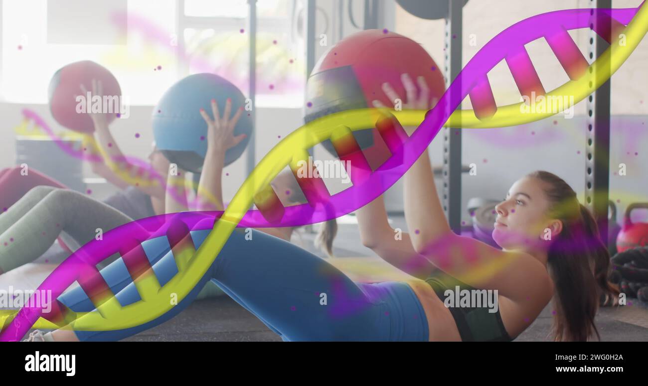 Image of dna strands over diverse women cross training with medicine balls at gym Stock Photo