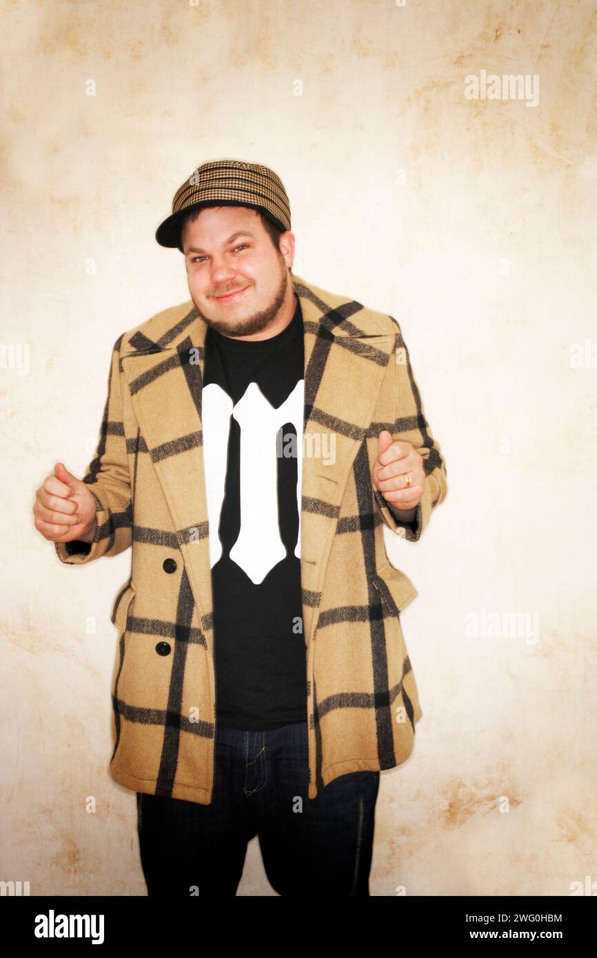 Young hip man wearing a coat and cap making a funny face at the camera. Stock Photo