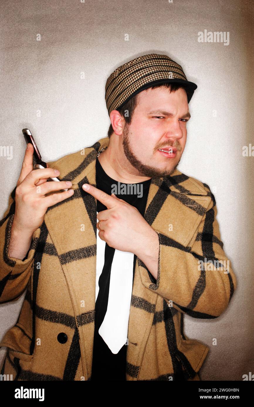 Young hip man pointing to his cell phone with an annoyed expression on his face. Stock Photo