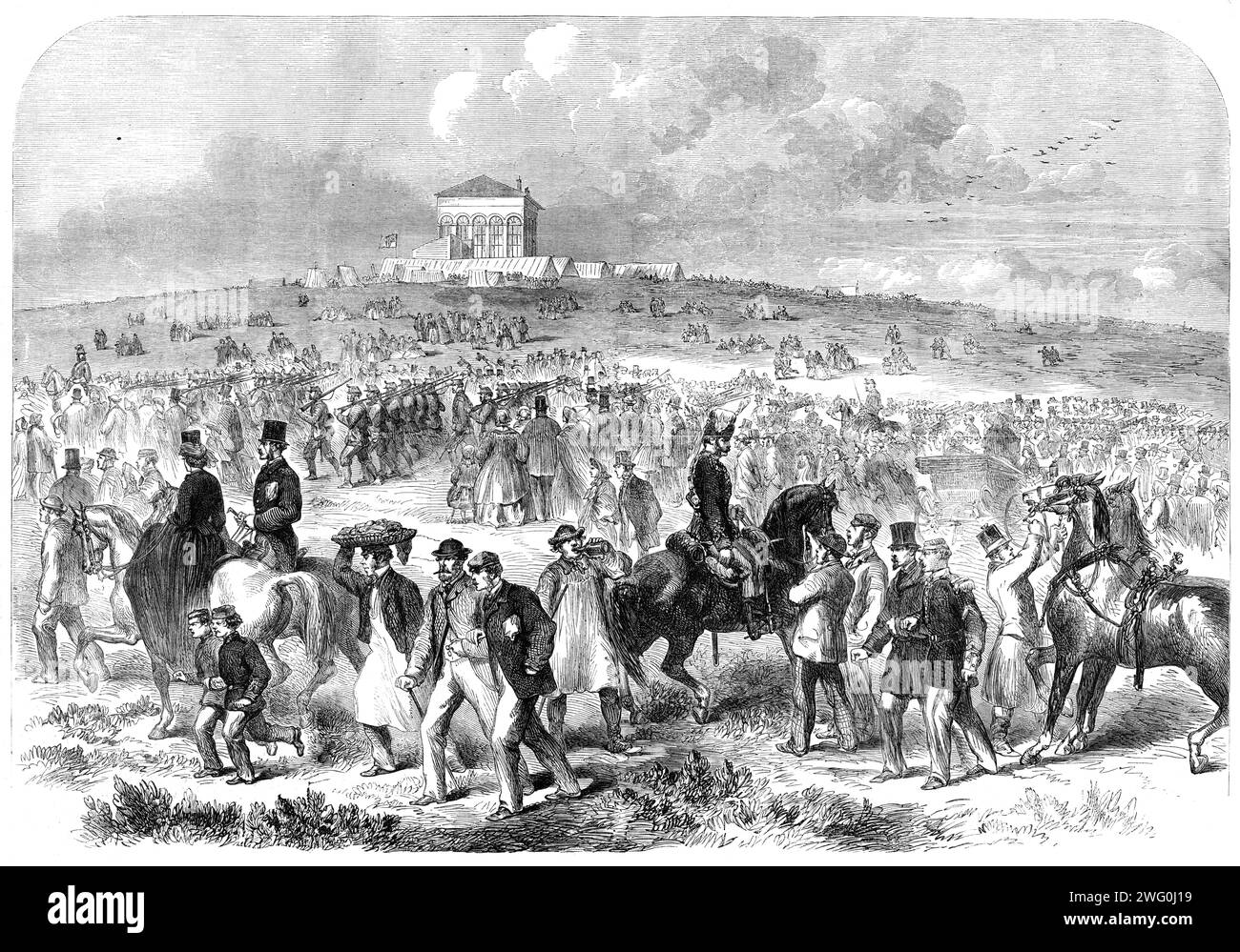 The Volunteer Field-Day at Brighton: arrival of volunteers on the racecourse, 1862. 'Nothing could be finer than the approach of something like 12,000 men in close column, at quick march, up the steep hill leading to the racecourse...The whole aspect of the field, as seen from the Grand Stand, was magnificent in the extreme...On each side, as far as the racecourse extended, was a dense body of spectators, which appeared to stretch away for miles...Again, in the fourth brigade of the second division...was a broad streak of scarlet, caused by the uniforms of the 3rd City of London and the 32nd M Stock Photo