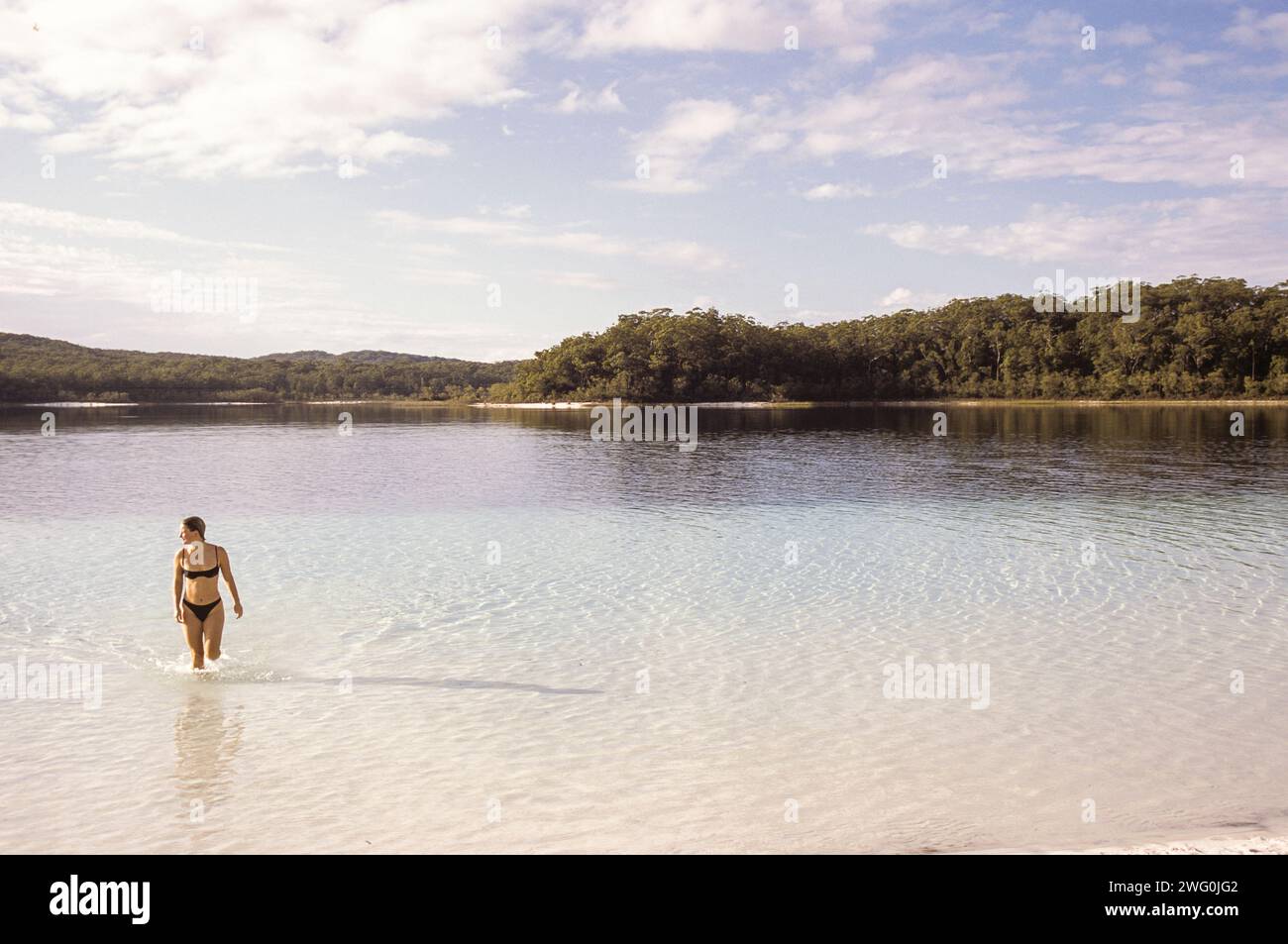 A woman exits the crystal clear waters of Lake McKenzie on Fraser Island, Queensland, Australia. Stock Photo