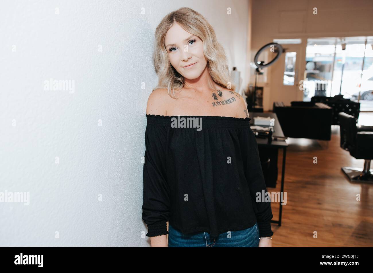 Female permanent makeup artist stands by a wall for headshot pictures Stock Photo