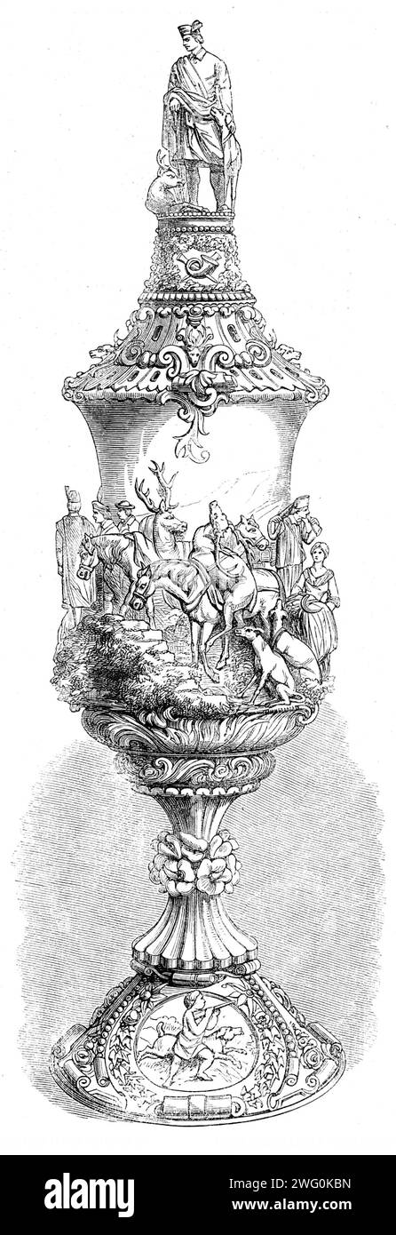 The International Exhibition: carved ivory cup, by F. B&#xf6;hler, in the Zollverein Department, 1862. The cup '...is surrounded by a relief copy of Landseer's &quot;Deerstalkers' Return,&quot; below which the rose, thistle, and shamrock are braided with the ornament. The base is set with medallions bearing emblems of the chase; and the whole is surmounted by a figure of the Prince of Wales in his Highland costume. The carving is delicate and fine and the figures are well rendered; yet, in point of design, there are certain defects arising from the high relief of the subject'. From &quot;Illus Stock Photo