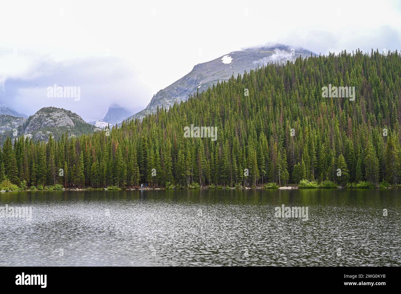 Mountain peak towering over a serene lake surrounded by majestic pine ...